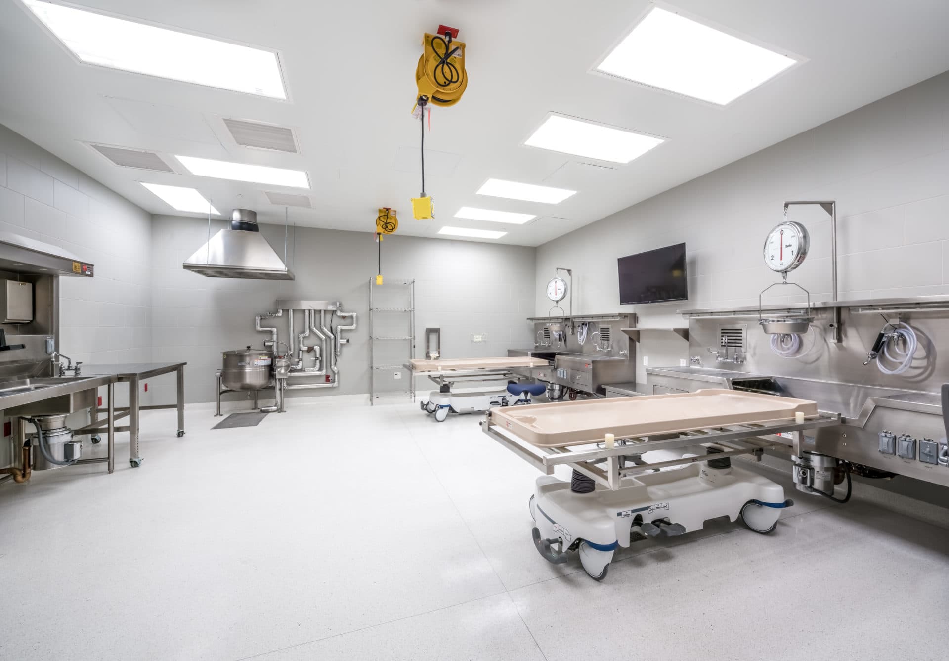 Clean white medical processing room with stainless steel equipment and overhead hoist