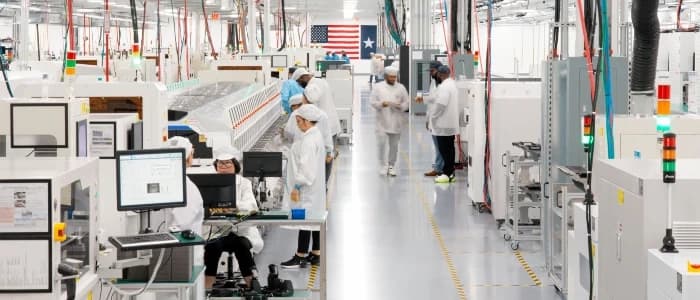 Cleanroom manufacturing floor with workers in white suits and automated assembly stations