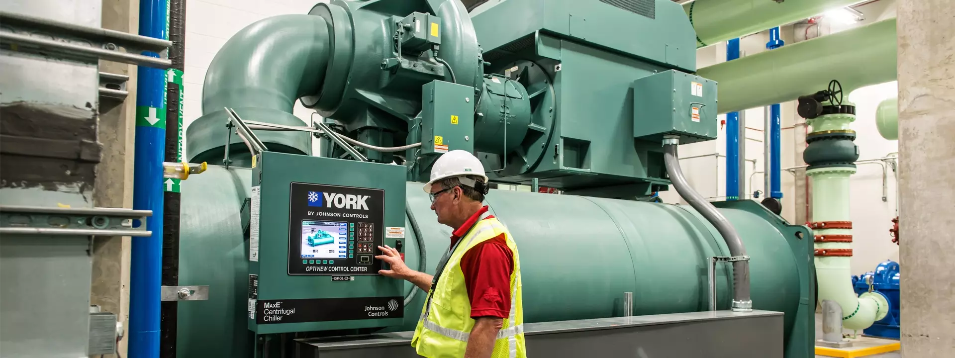 Technician in hi-vis vest operating York centrifugal chiller control panel